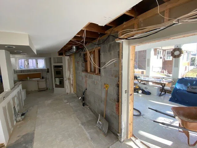 Kitchen before the wall is removed, with its existing studs and ceiling exposed